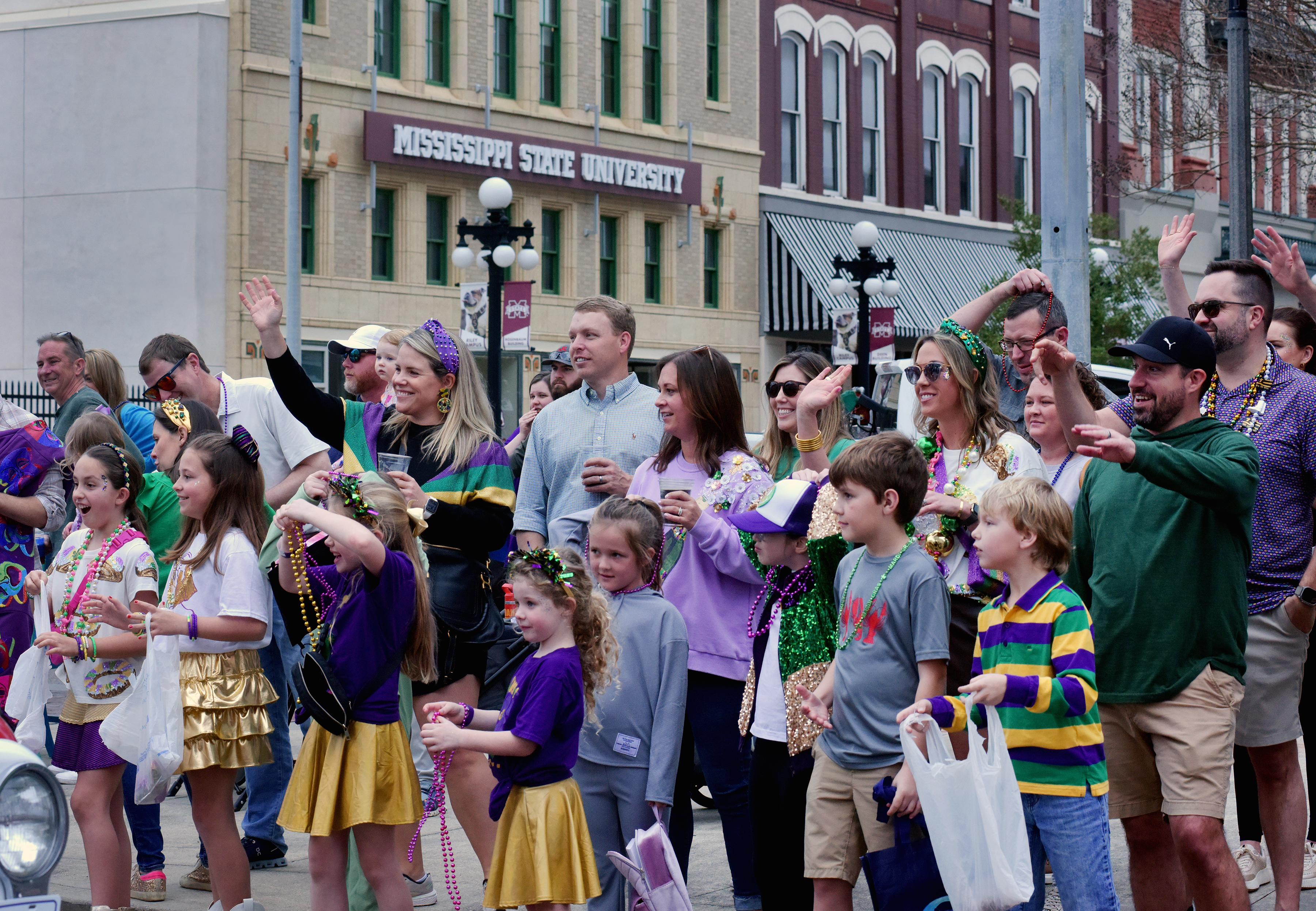 Revelers gather in front of MSU-Meridian's Riley Campus to catch beads in the Meridian Mardi Gras Parade. Morgan Dudley,  director of conferences, events and operations, served as queen of the parade on Saturday. (Photo by Marianne Todd) 