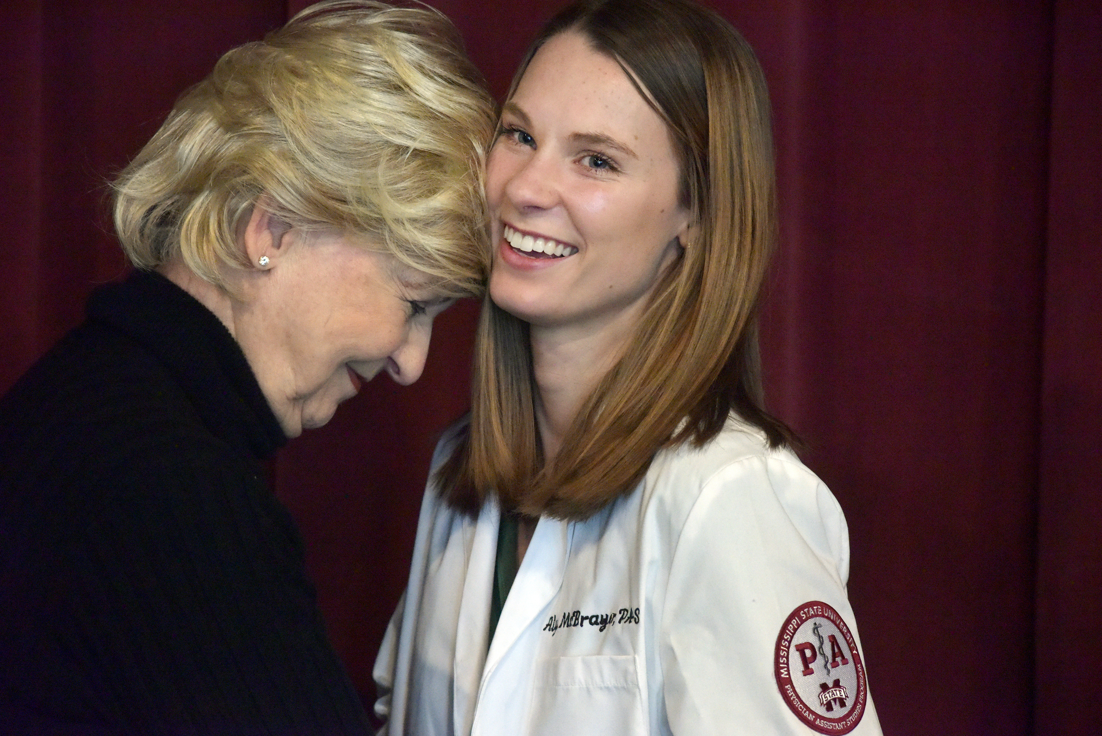 Alyse McBrayer meets with her grandmother, Christine Riley, after earning her white coat in a ceremonial rite of passage on Thursday. The white coat is symbolic that McBrayer and the other 27 students in her Master of Physician Assistant Studies cohort are prepared to enter clinical rotations. 