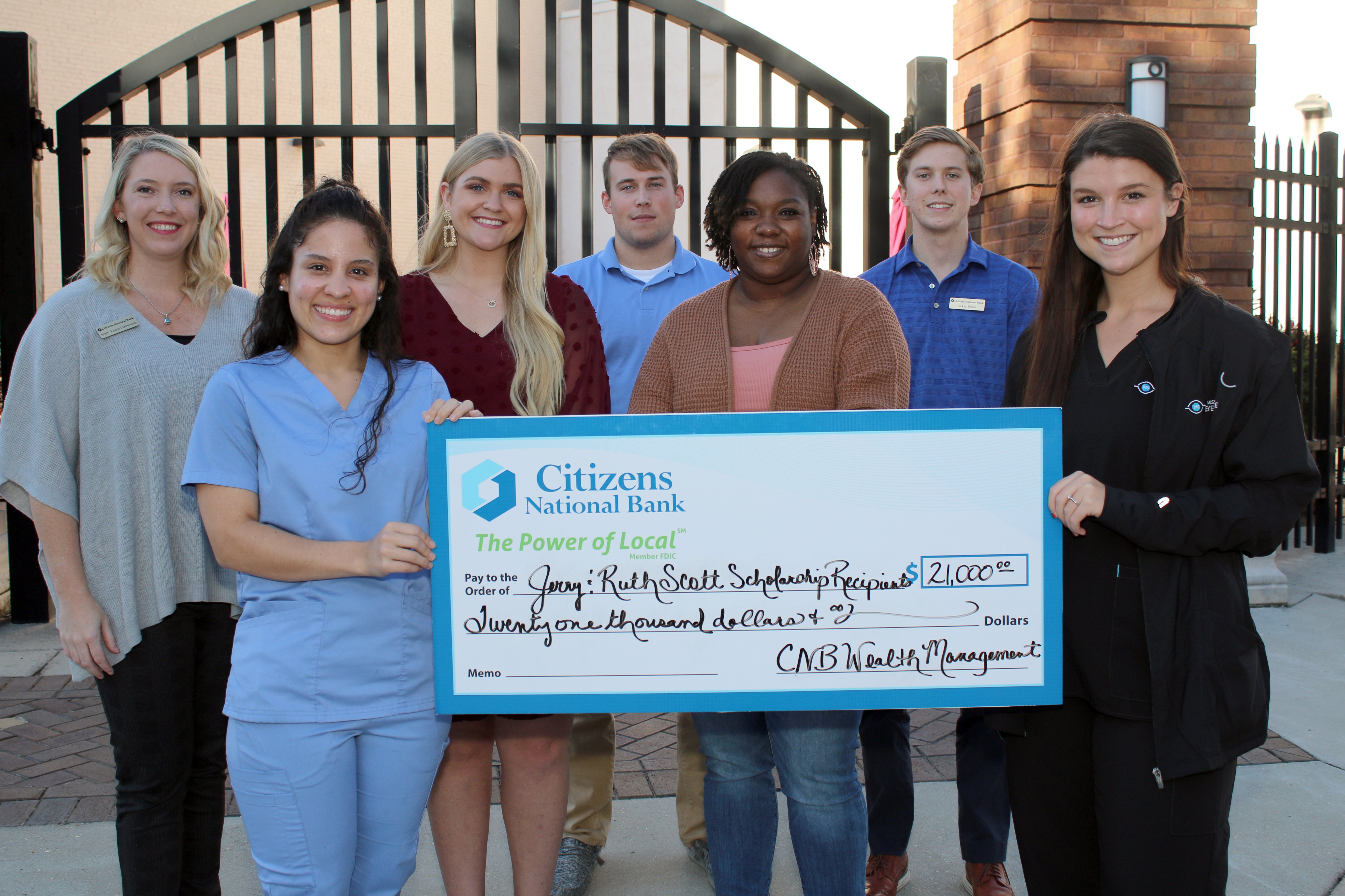 Five students and two employees from Citizens National Bank with large check outside Riley Courtyard in downtown Meridian