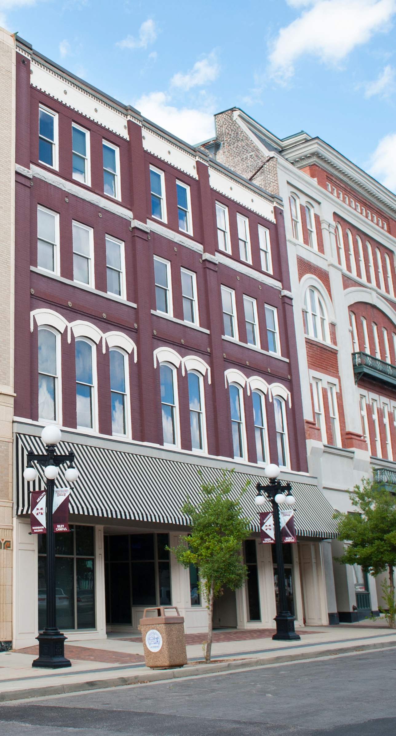 Deen Building with maroon exterior and a black and white awning 