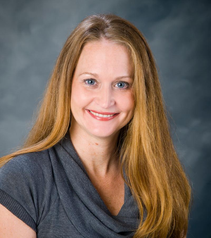 Portrait of Dr. Kimberly Hall wearing a grey top with long brown hair