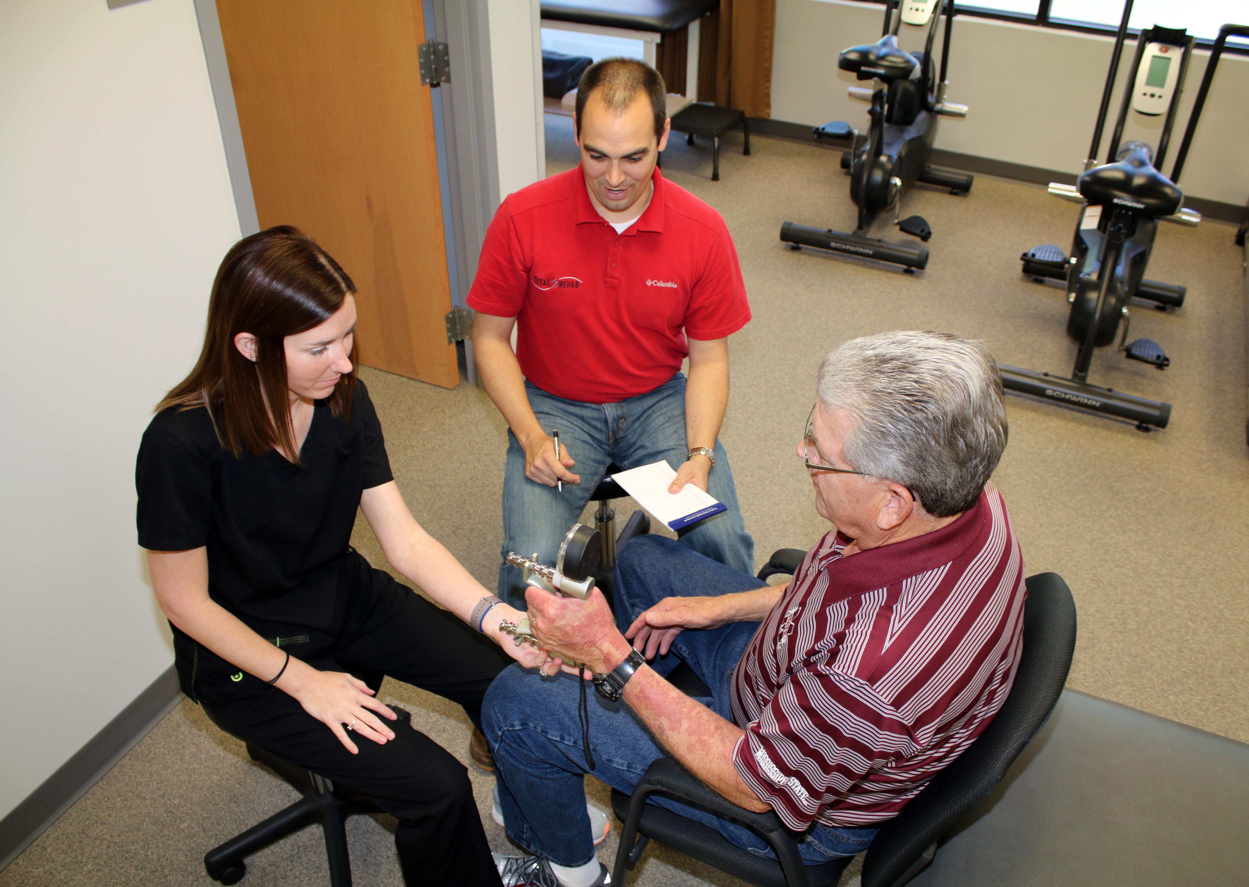 Dr Stephen Kay of Total Rehab and MSU-Meridian kinesiology student, Anna Katherine Russell, test grip strength on Tim Donaldson of Meridian.