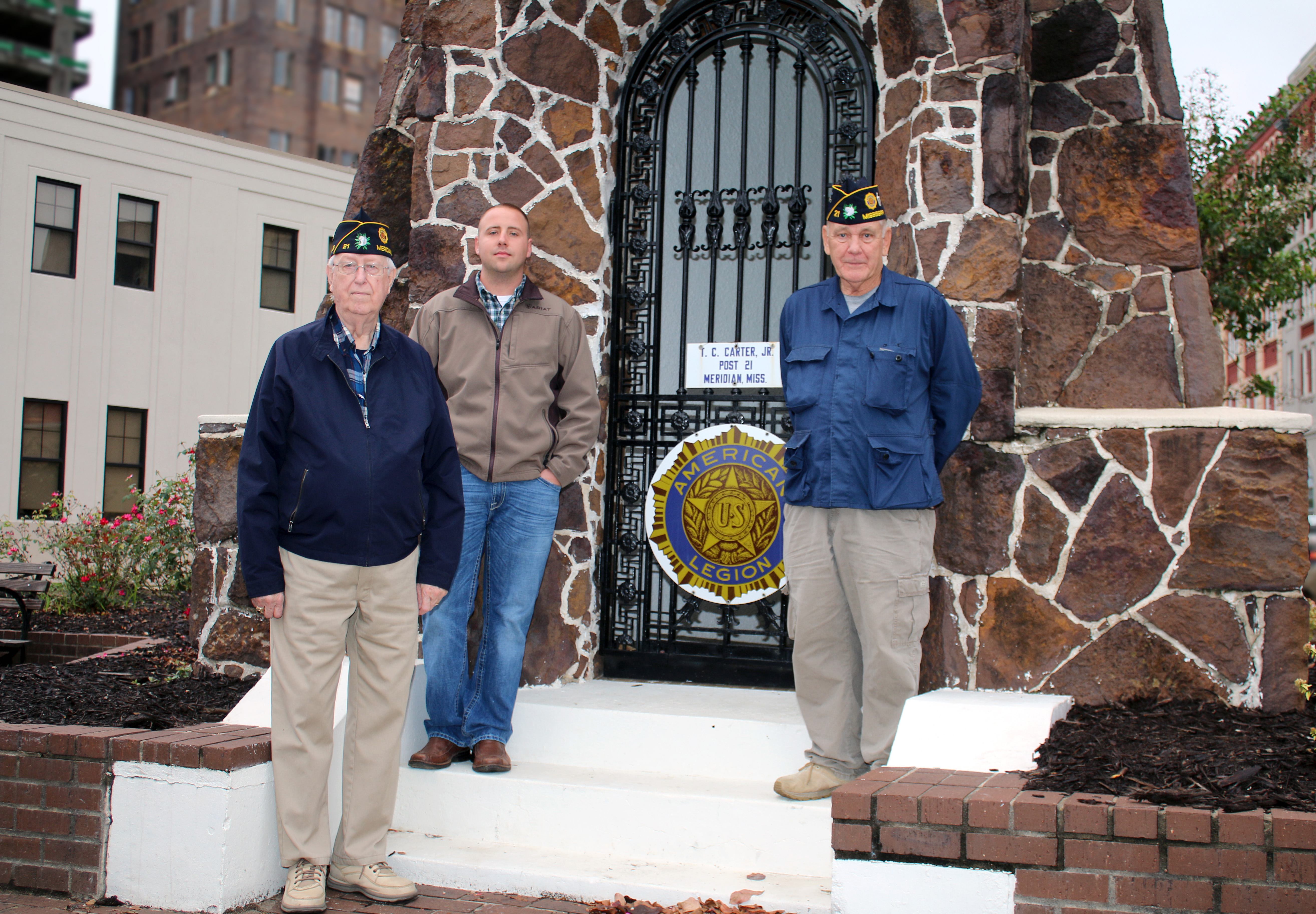 Two members of the American Legion stand with scholarship recipient at the Doughboy monument in downtown Meridian