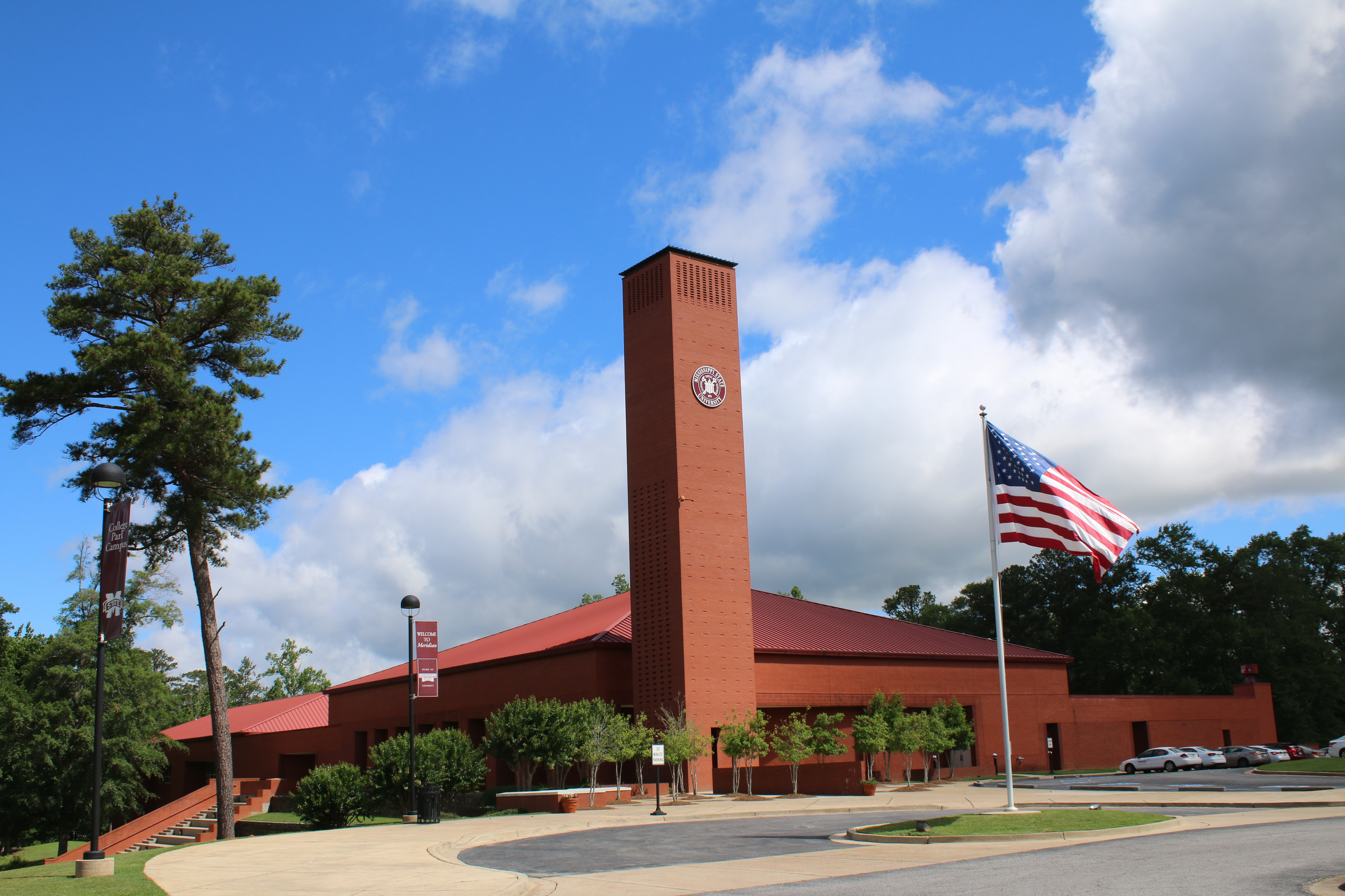 The front of College Park Campus, red brick building with tall brick tower and MSU seal, with American flag waving in front