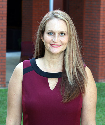 portrait of Dr. Kimberly Hall wearing a maroon sleeveless top with a black collar. She has long highlighted hair.