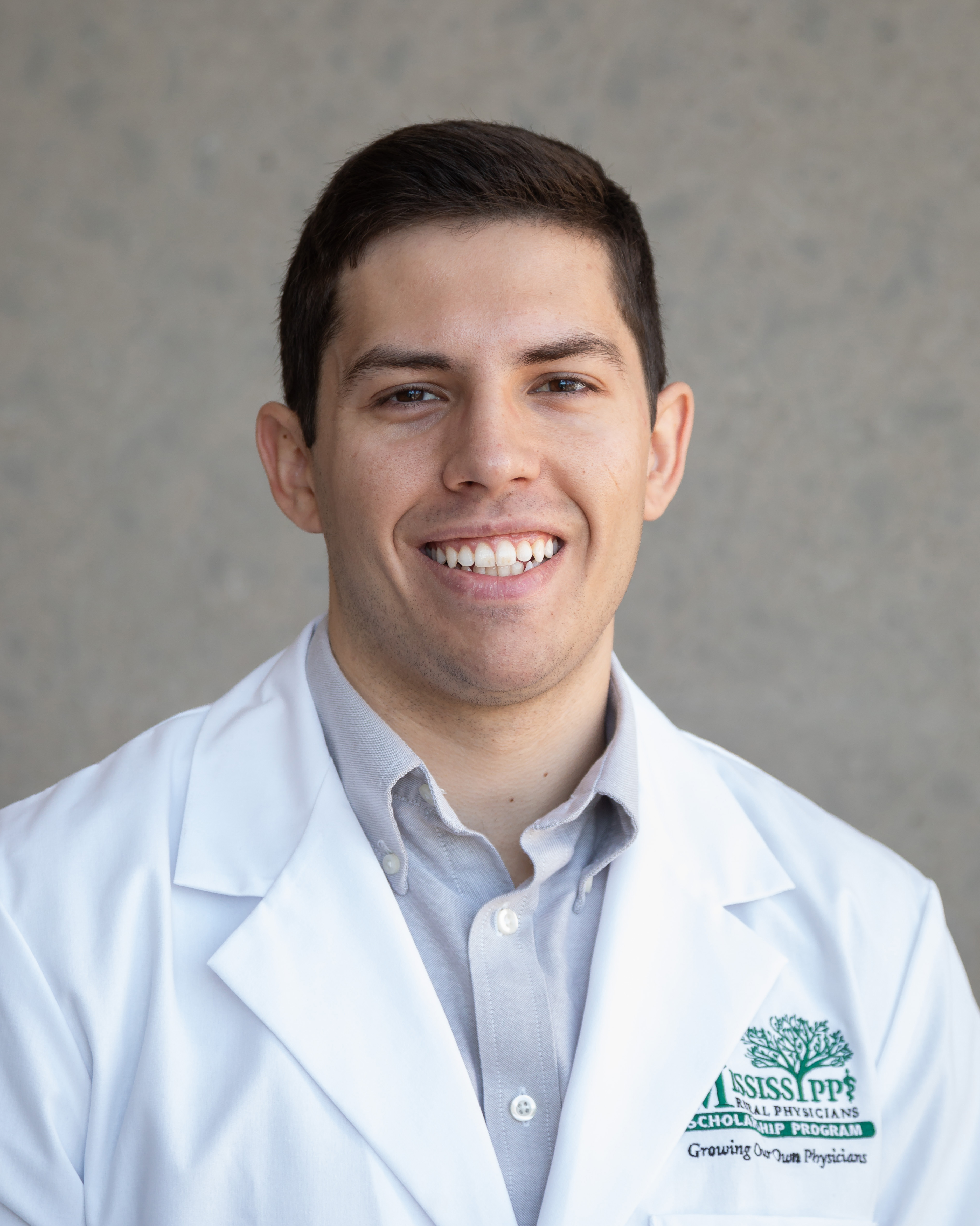 A portrait of Emilio Suarez wearing his white coat received for the Mississippi Rural Physicians Scholarship Program