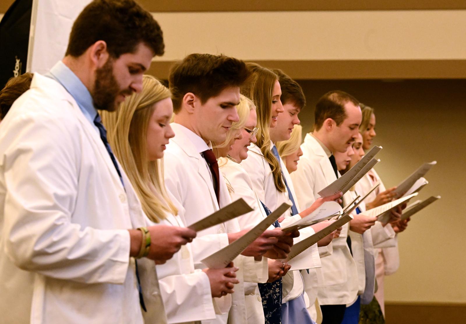MSU-Meridian Physician Assistant Studies students in a line with white coats holding pieces of paper