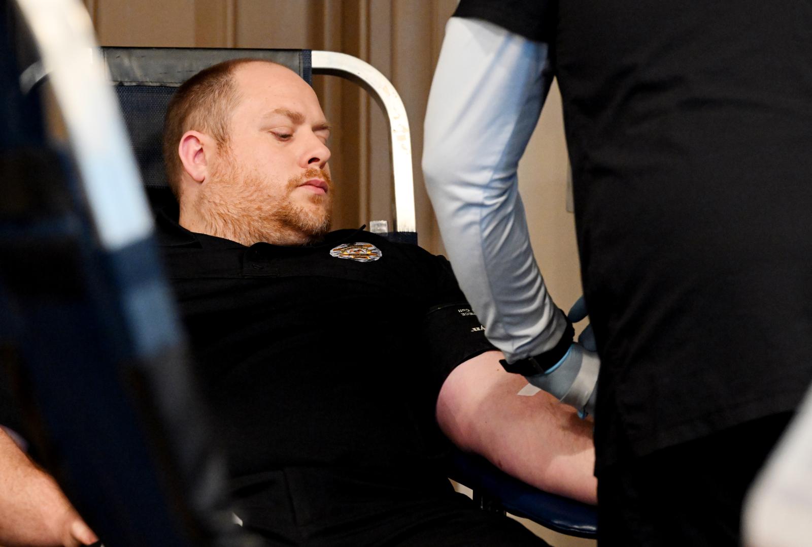 Person in black shirt sitting in chair about to donate blood