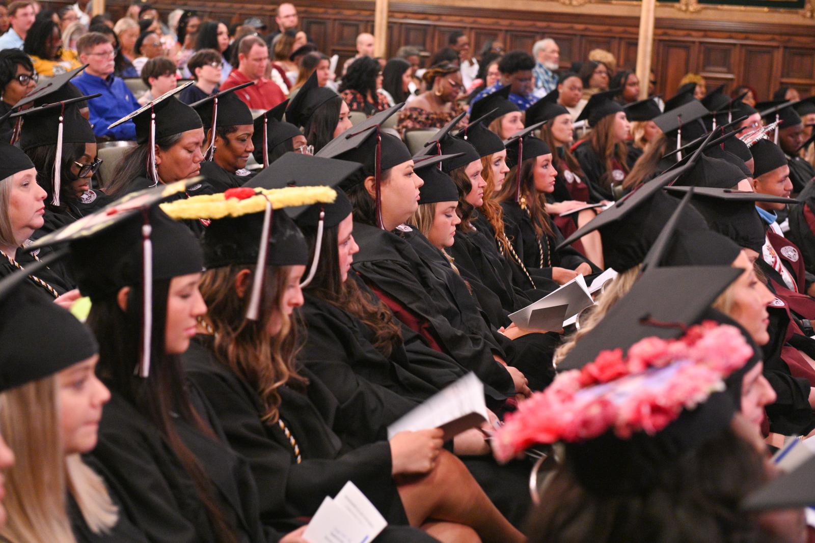 Students in commencement regalia sitting in rows in theater for commencement ceremonies.