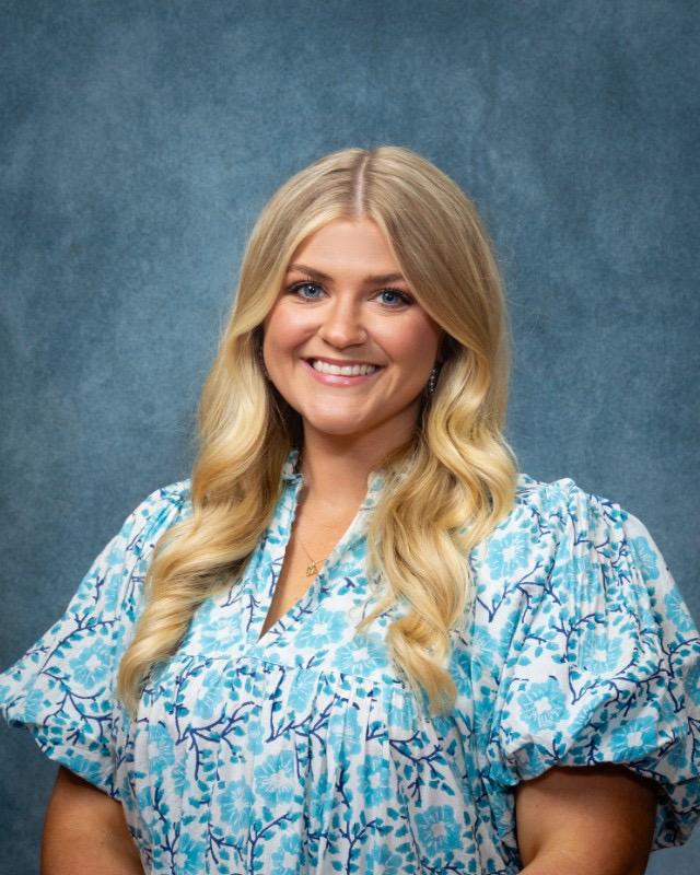 Photo of Catherine McGowin, a three-time graduate of MSU-Meridian’s Division of Education, is the 2026 Mississippi History Teacher of the Year and a national top 10 finalist. She has long hair and is wearing a blue pattern dress.