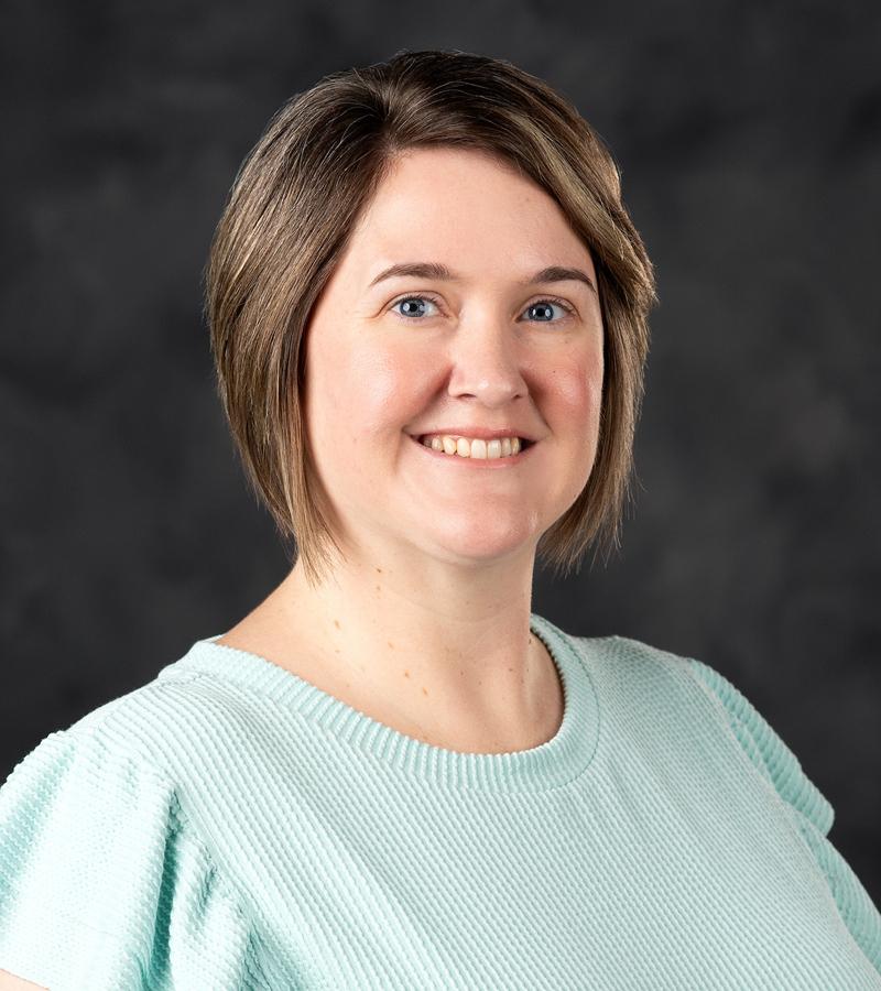 Portrait of Serena Sanders with short hair wearing a light blue top.